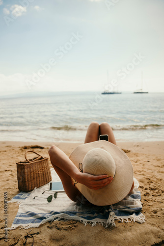 Caucasian girl tanning on beach wearing straw sunhat 