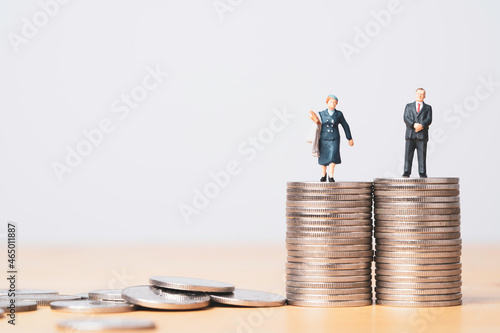 Miniature figure of businessman standing on equal coins stacking of  businesswoman for equality of gender male and female of income and salary concept. photo