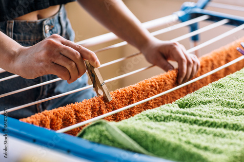 Woman hanging clean laundry with clothespins on washing line outdoors, closeup