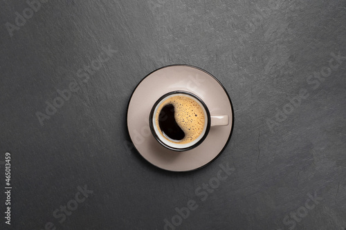 a cup of coffee with beautiful foam near coffee beans are scattered on a black stone background top view copy space