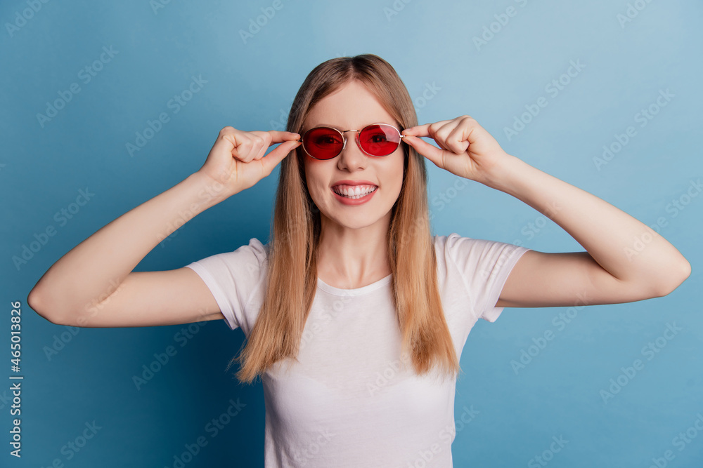 Portrait of positive charming lady toothy beaming smile wear sunglass white t-shirt isolated on blue color background Portrait of positive charming lady toothy beaming smile wear sunglass white t-shirt isolated on blue color background