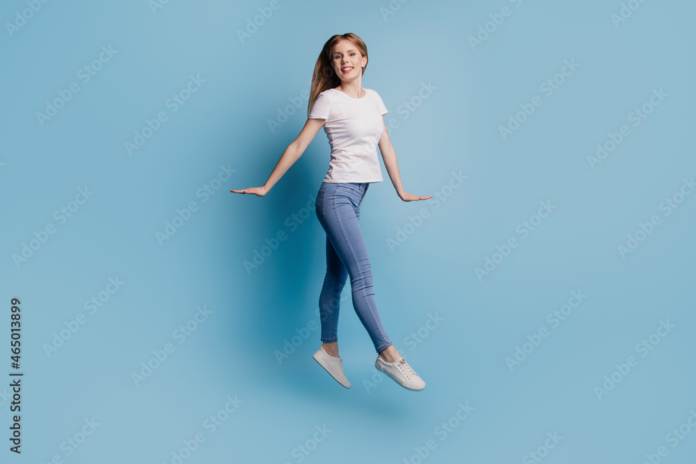 Photo of funny positive blonde charming lady carefree jump wear casual clothes on blue color background