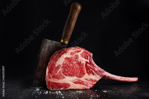 Fresh tomahawk steak on old board photo
