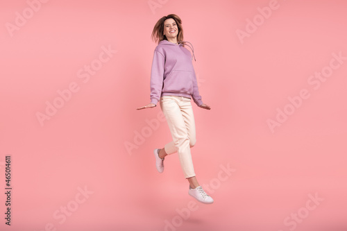 Full body profile side photo of mature woman have fun jump up playful ait fly isolated pink color background