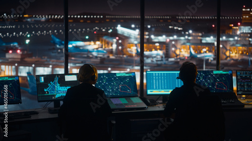 Diverse Air Traffic Control Team Working in a Modern Airport Tower at Night. Office Room is Full of Desktop Computer Displays with Navigation Screens, Airplane Flight Radar Data for Controllers.