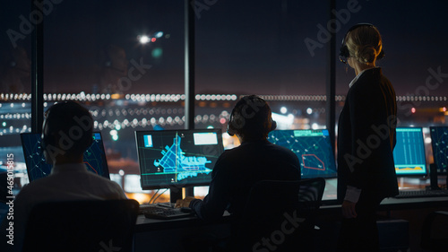 Fotografiet Female and Male Air Traffic Controllers with Headsets Talk in Airport Tower at Night