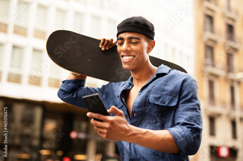 African man with skateboard. Young handsome man using the phone photo