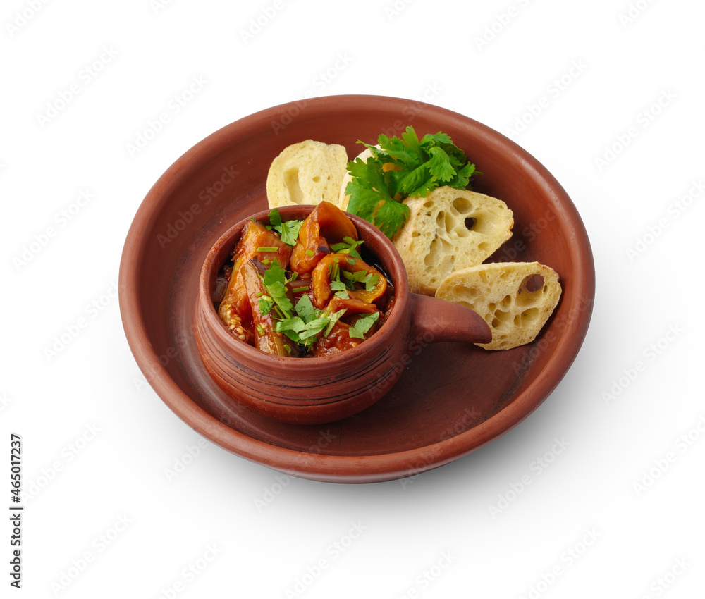 Steamed pepper and eggplant appetizer served with bread slices on clay plate