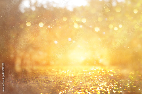 blurred abstract photo of light burst among trees and glitter golden bokeh lights