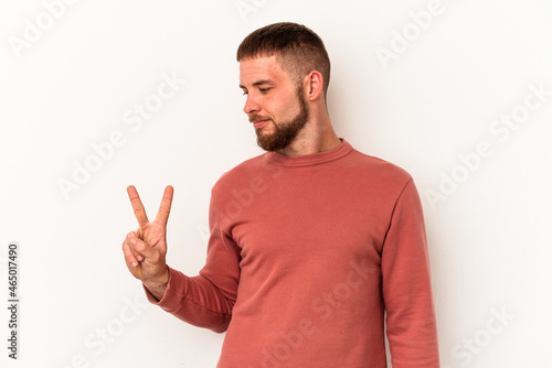 Young caucasian man with diastema isolated on white background joyful and carefree showing a peace symbol with fingers.