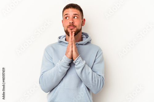 Young caucasian man with diastema isolated on white background praying, showing devotion, religious person looking for divine inspiration.