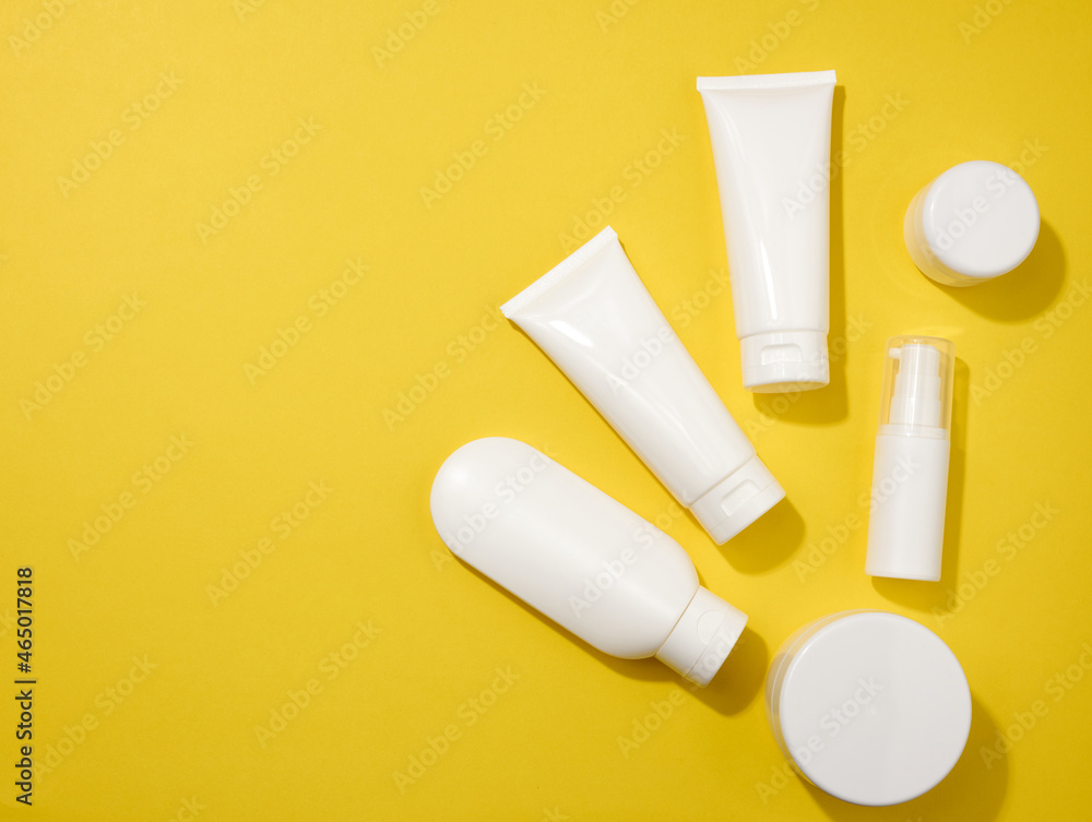 jar, bottle and empty white plastic tubes for cosmetics on a yellow background. Packaging for cream, gel, serum, advertising and product promotion jar, bottle and empty white plastic tubes for cosmetics on a yellow background. Packaging for cream, gel, serum, advertising and product promotion