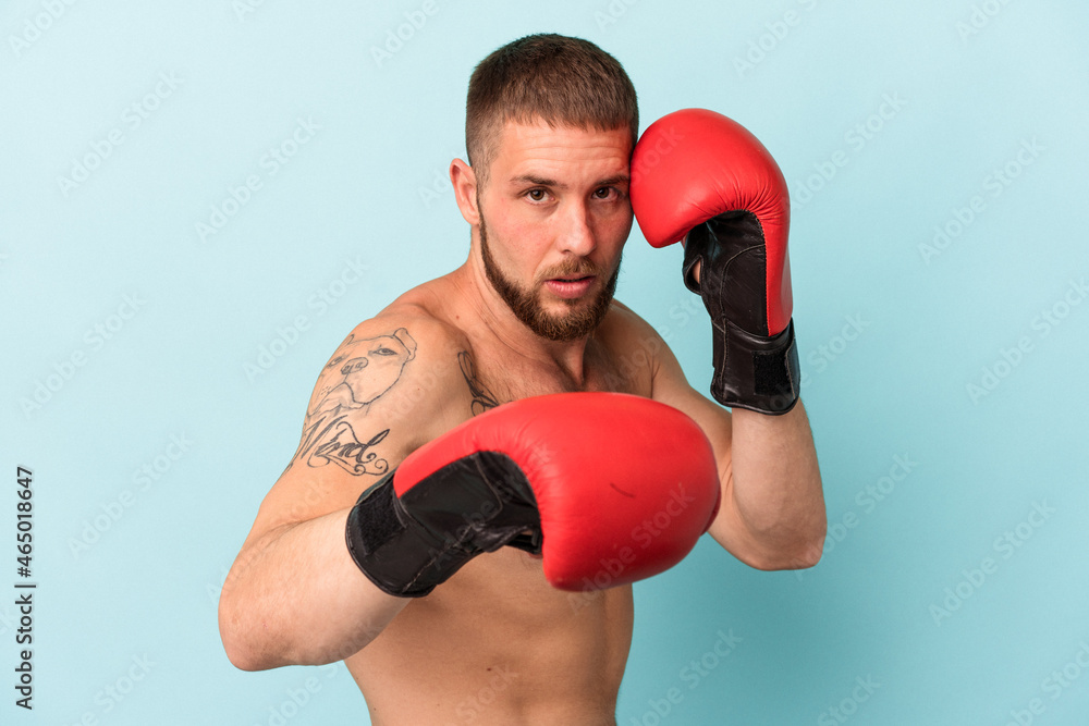 Young caucasian man practicing boxing isolated on blue background