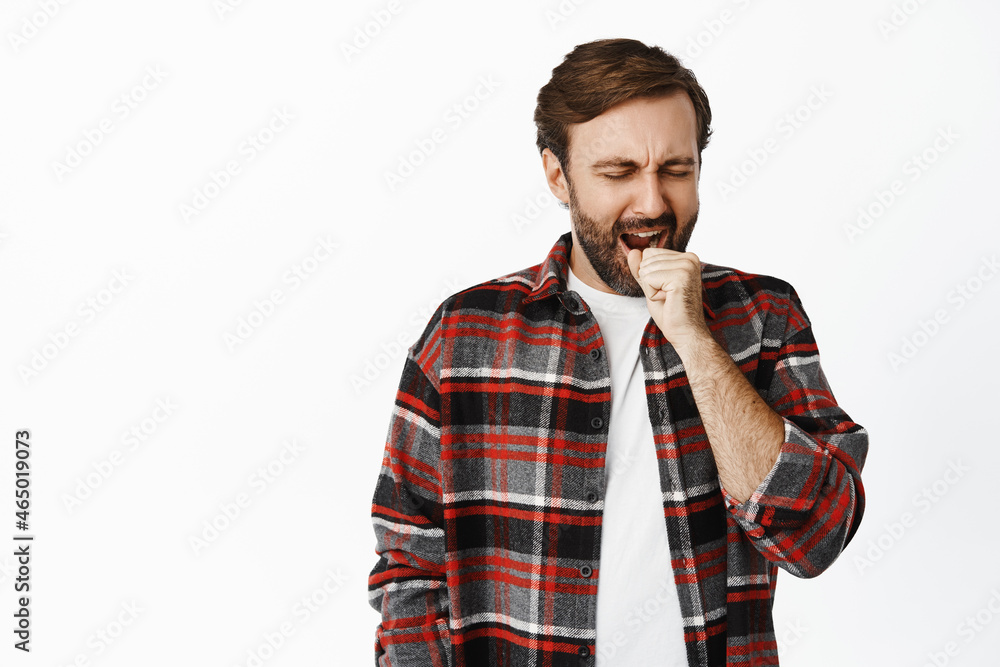 Image of bearded guy yawning, cover mouth yawn, falling asleep, standing over white background Image of bearded guy yawning, cover mouth yawn, falling asleep, standing over white background