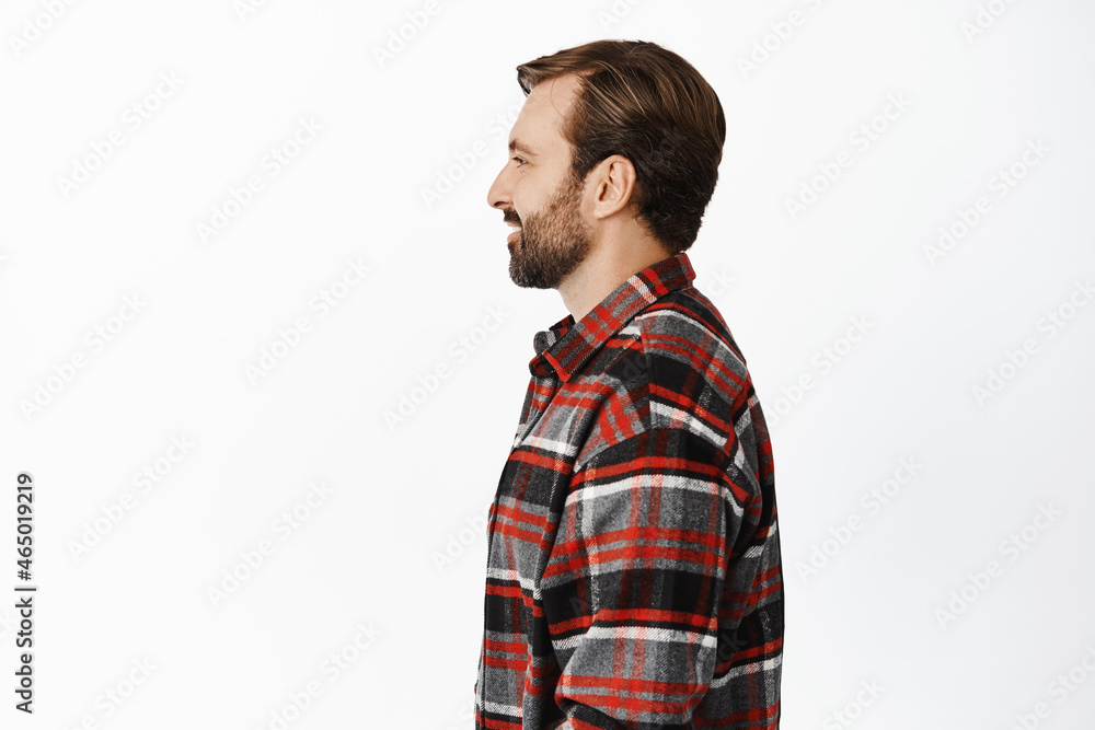 Profile portrait of handsome brunette adult man with beard, looking left and smiling, standing in casual clothes over white background Profile portrait of handsome brunette adult man with beard, looking left and smiling, standing in casual clothes over white background
