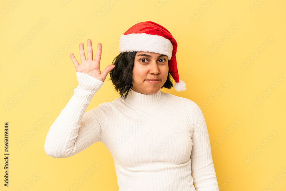 Young latin woman celebrating christmas isolated on yellow background smiling cheerful showing number five with fingers. Young latin woman celebrating christmas isolated on yellow background smiling cheerful showing number five with fingers.