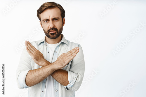 Very bad. Serious and disappointed man showing cross sign and furrow eyebrows upset, prohibit, disagree and reject offer, tell to stop, white background