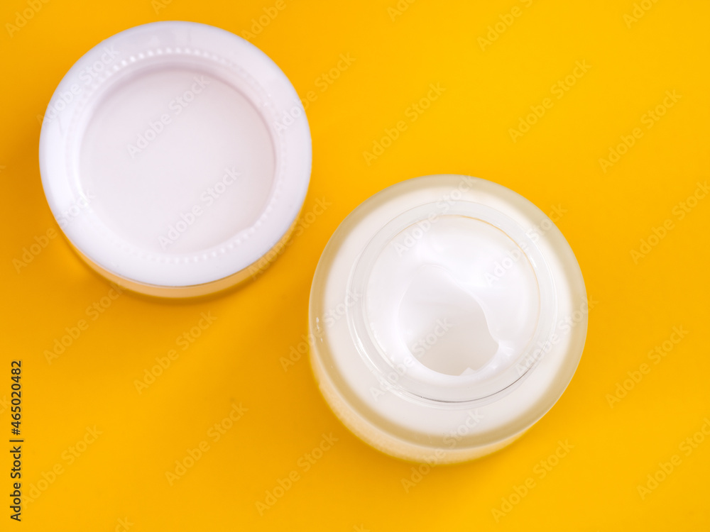 Face cream in an open jar. Yellow background. Face cream in an open jar. Yellow background.