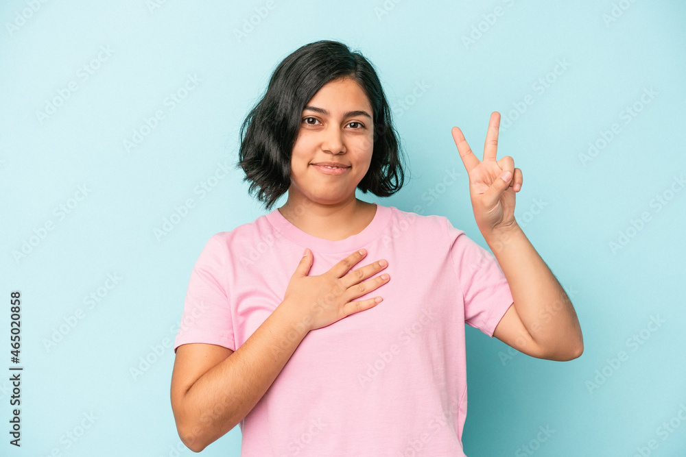 Young latin woman isolated on blue background taking an oath, putting hand on chest. Young latin woman isolated on blue background taking an oath, putting hand on chest.