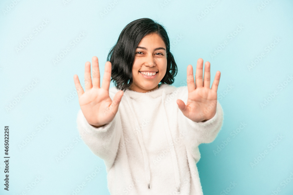 Young latin woman isolated on blue background showing number ten with hands. Young latin woman isolated on blue background showing number ten with hands.