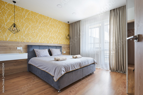 a bed with a soft headboard in a Scandinavian-style bedroom in yellow tones