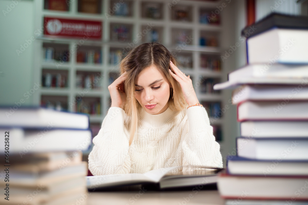 A tired student is studying in the school library. A tired student is studying in the school library.