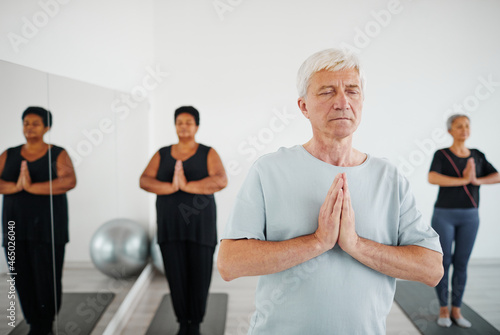Portrait of senior man with eyes closed practicing meditation during group yoga class