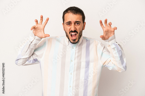 Young caucasian man isolated on white background showing claws imitating a cat, aggressive gesture. © Asier