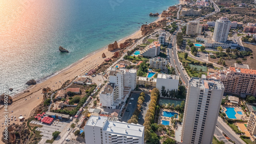 Aerial view of the city of Portimao over residential buildings, high-rise buildings, on the beach Praia de Rocha with tourists. Sunny day