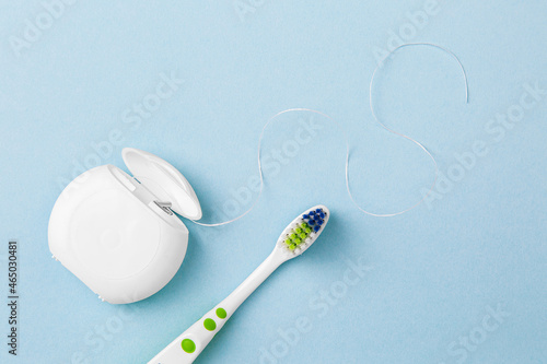 dental floss and toothbrush on blue background. Care of teeth health. Everyday routine teeth cleaning and flossing