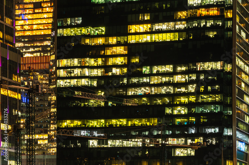 Skyscraper windows glow at night. Modern office buildings at night.