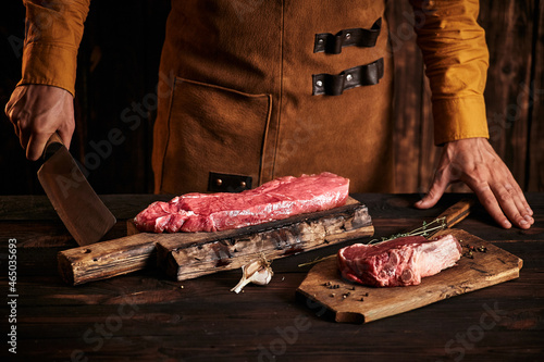 A butcher with a knife in a leather apron holds a piece of meat.