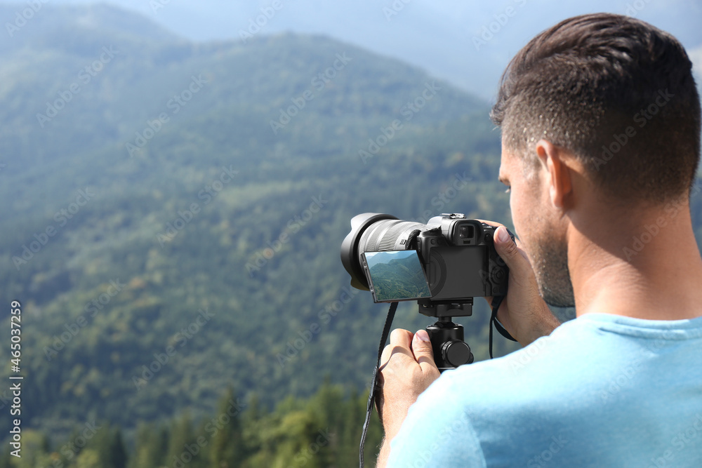 Man taking photo of nature with modern camera on stand outdoors