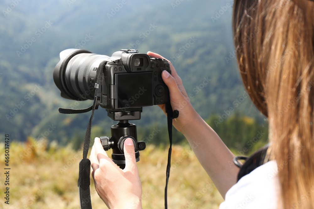 Woman taking photo of nature with modern camera on stand outdoors Woman taking photo of nature with modern camera on stand outdoors