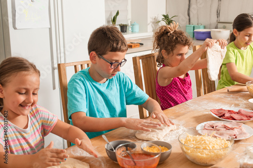 the kids in the kitchen preparing pizza dough