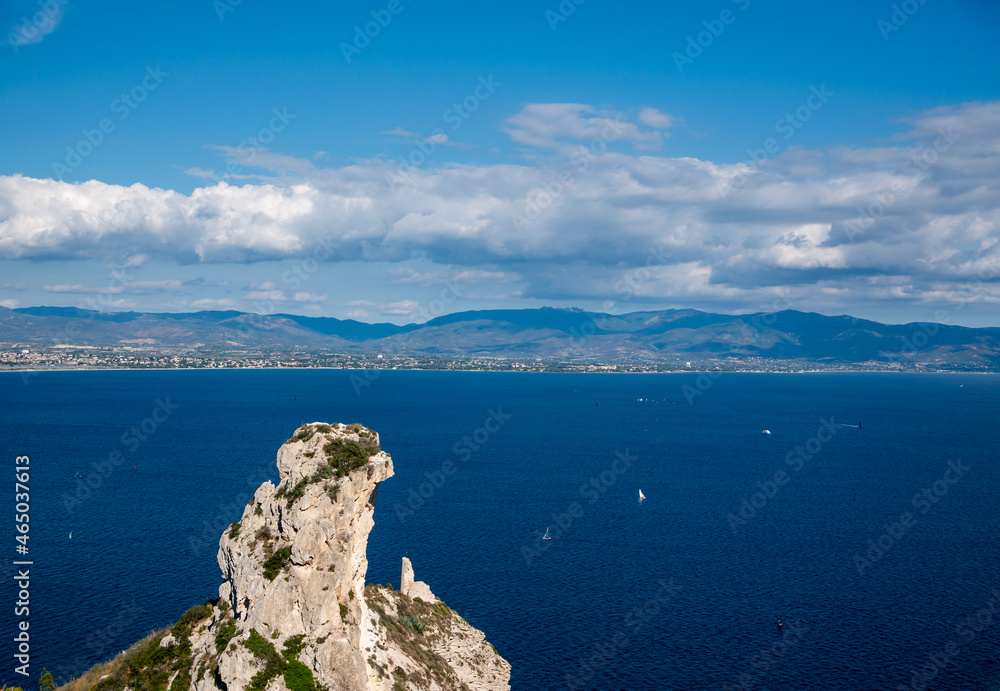rock formation called Sella Del Diavolo in Sardinia with mountains and city in distance
