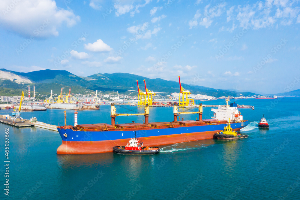 Industrial seaport Novorossiysk , top view. Bulk carrier, Multipurpose or General cargo enters the port using tugs