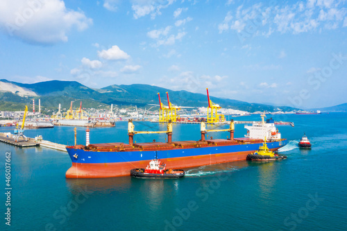 Industrial seaport Novorossiysk , top view. Bulk carrier, Multipurpose or General cargo enters the port using tugs