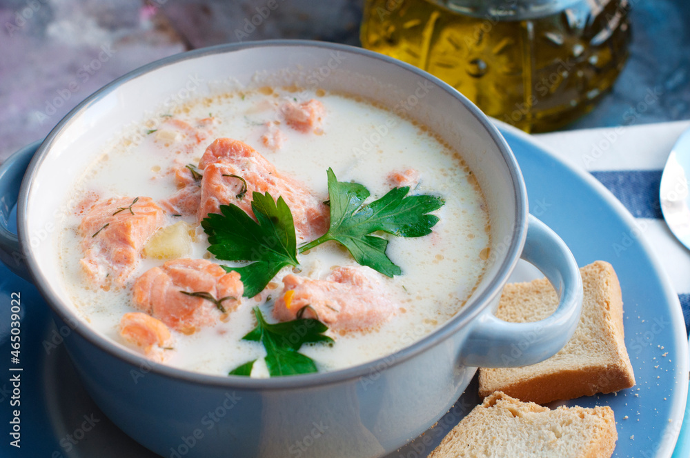 Creamy salmon soup Kalakeitto with salmon, carrot, parsley, onion, garlic, potatoes, croutons and spoon in blue bowl. Traditional Finnish hot soup Creamy salmon soup Kalakeitto with salmon, carrot, parsley, onion, garlic, potatoes, croutons and spoon in blue bowl. Traditional Finnish hot soup