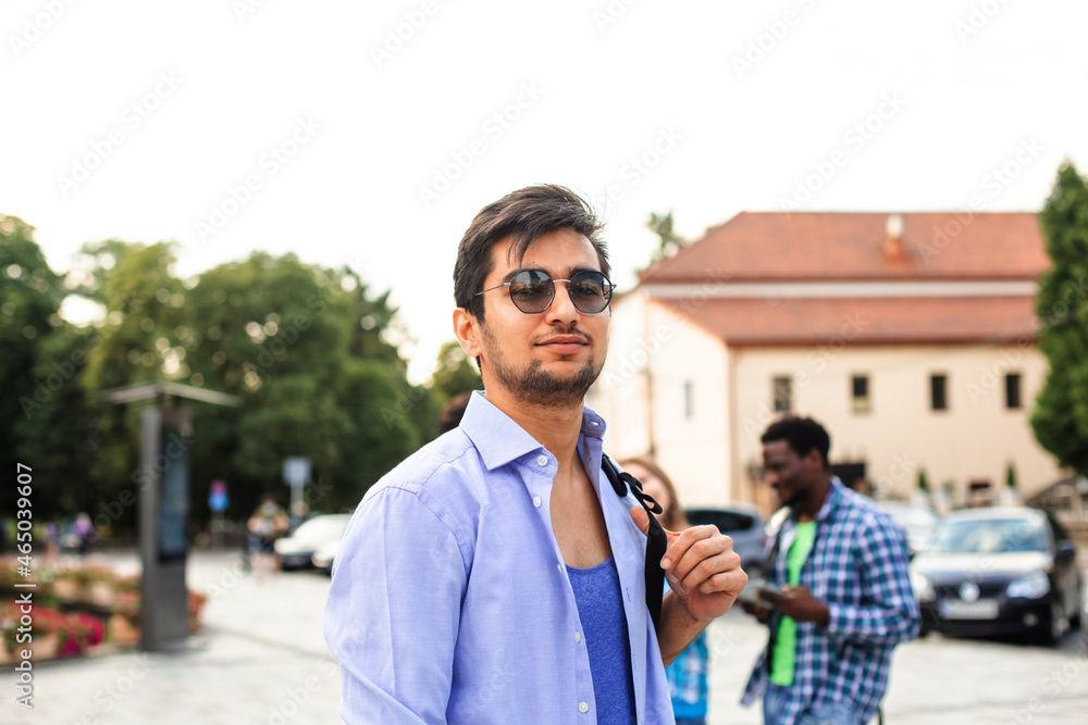 The handsome indian student is hugging a stack of books outdoors The handsome indian student is hugging a stack of books outdoors