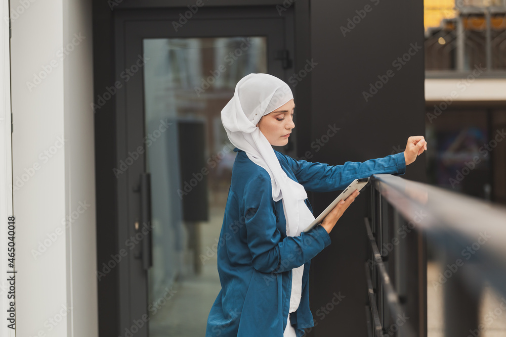 Young asian muslim woman in head scarf smile with mobile tablet and copy space