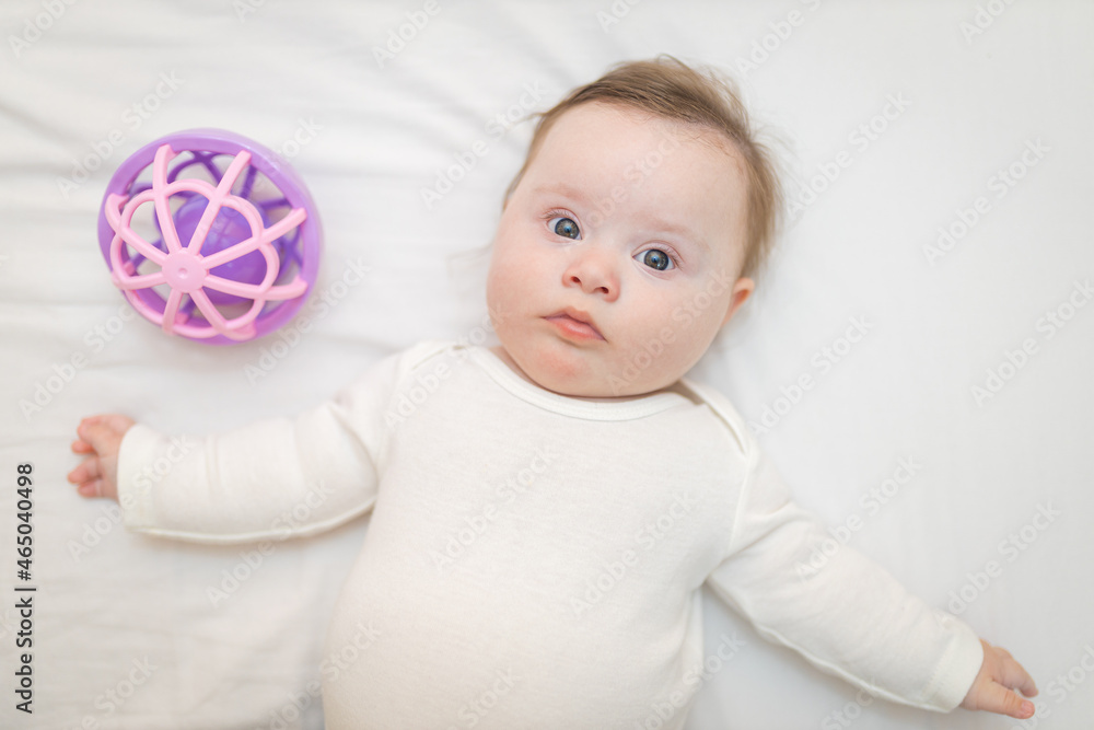 Cute Baby Girl Infant Stand on Back in Crib near a Sensory Toy Cute Baby Girl Infant Stand on Back in Crib near a Sensory Toy