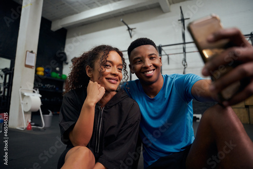 African American friends sitting on the floor and taking a photo together on the phone. African American couple taking a selfie together. High quality photo