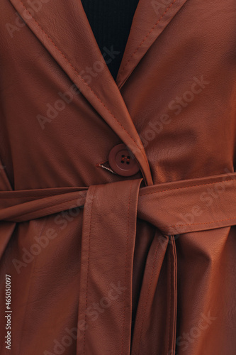 Street style fashion details of autumn trench, leather long stylish brown coat. Female outfit. Vertical