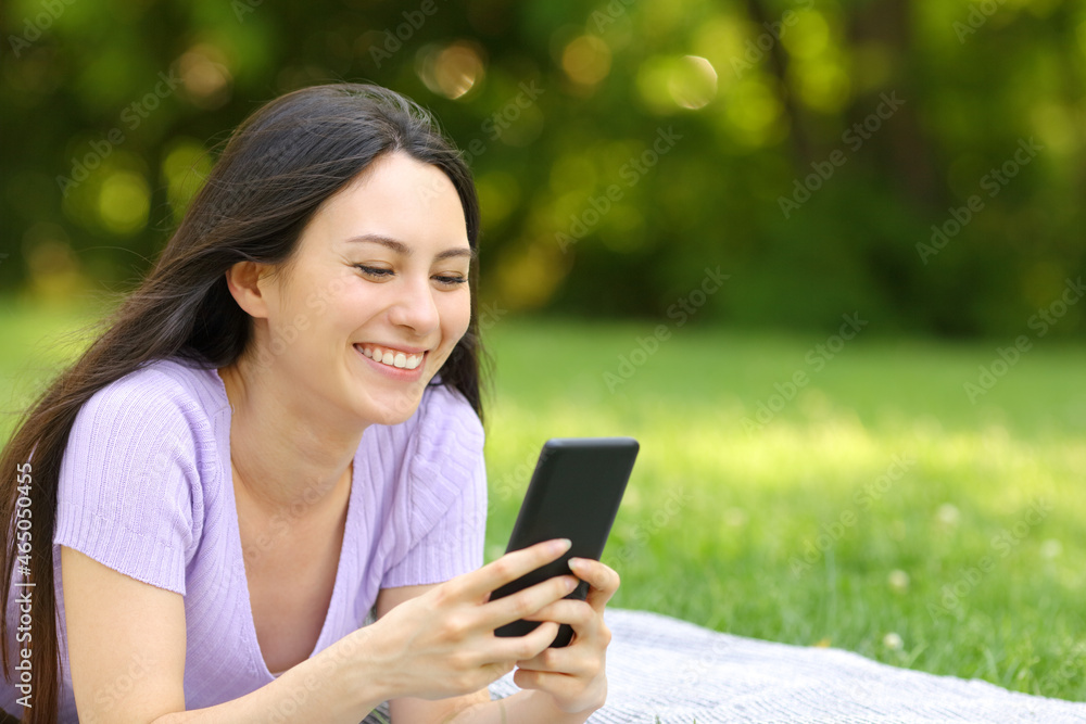 Fototapeta premium Happy asian woman checking mobile phone in a park