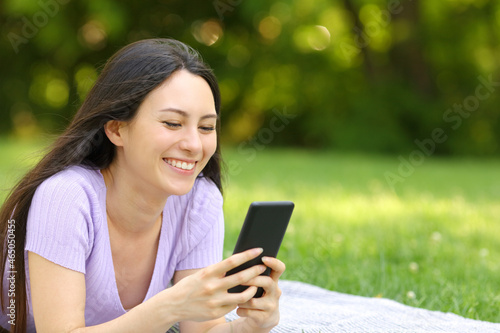 Happy asian woman checking mobile phone in a park