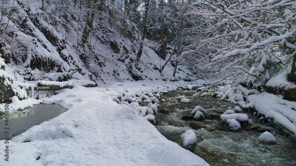 Aerial View Along a Calm Mountain River Surrounded By Magical Snow-covered Trees. Fabulous Light of Sun Rays on a Snowy Background in the Winter Forest. Magical White Winter Fairy Tale in the Forest. Aerial View Along a Calm Mountain River Surrounded By Magical Snow-covered Trees. Fabulous Light of Sun Rays on a Snowy Background in the Winter Forest. Magical White Winter Fairy Tale in the Forest.