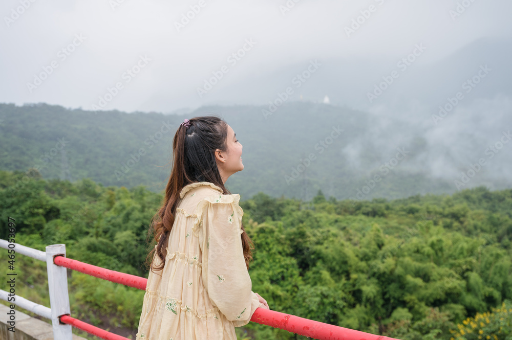 Asian woman relaxing and looking with foggy mountain view on rainy seaso