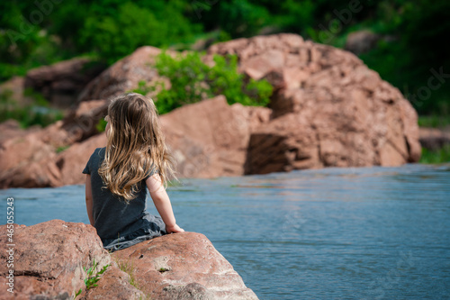 Girl staring sitting by the water trees rock formation natural nature 
