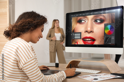 Professional African American retoucher working with graphic tablet at desk in photo studio © New Africa